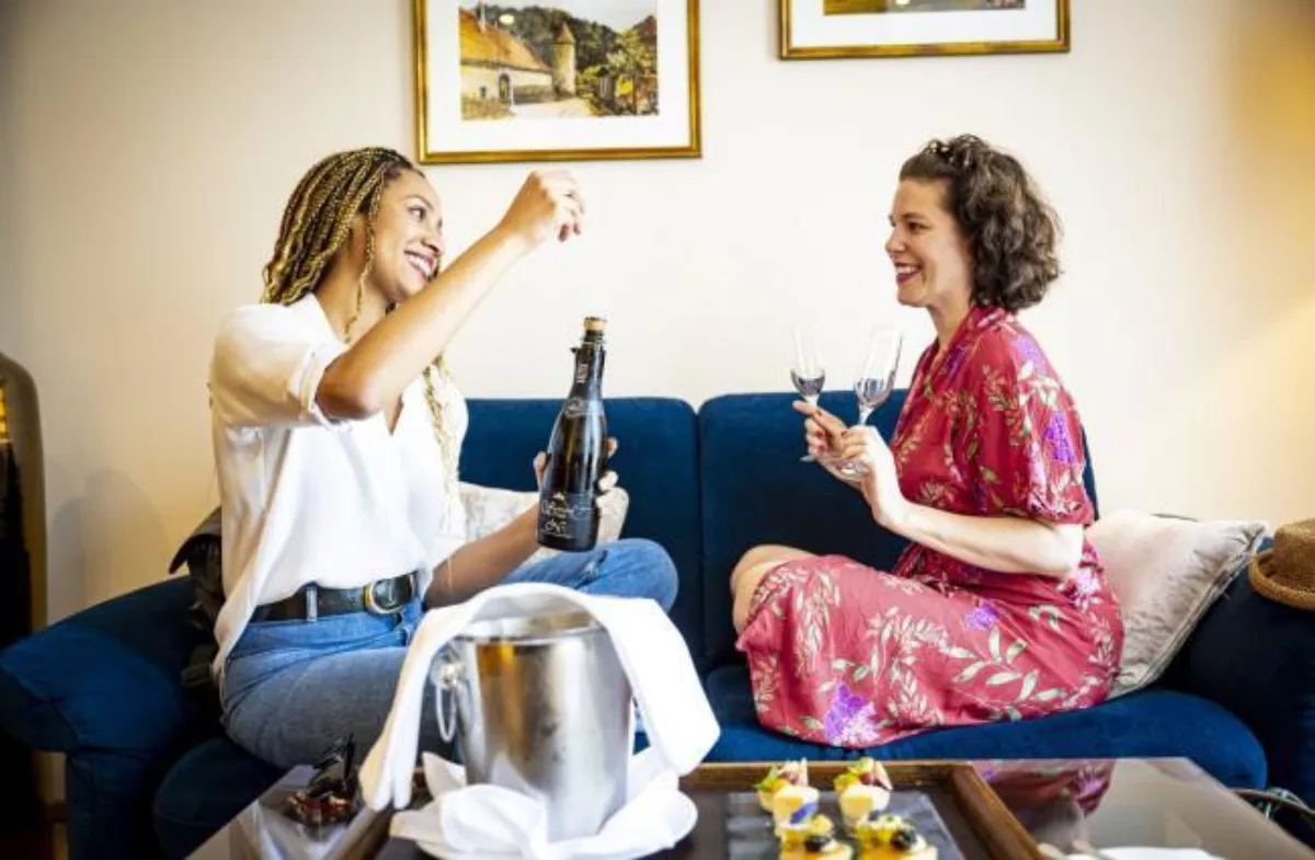 Freundinnen beim Öffnen einer Flasche Sekt in einem Deluxe Zimmer im Hotel Schlosspark Mauerbach